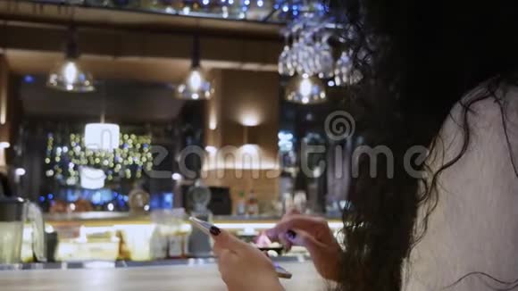 餐馆里留着卷发的漂亮女孩正在摸电话微笑着视频的预览图