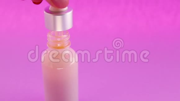 女性手拿化妆品吸管与天然补救在玻璃瓶上的粉红色背景视频的预览图