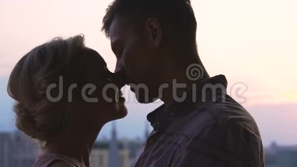 年轻夫妇在天空城市风景背景下接吻青春的爱情相聚视频的预览图