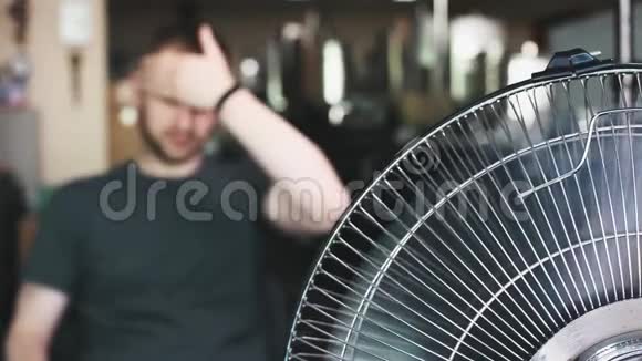 年轻人在炎热的一天面前吹风扇夏季炎热视频的预览图