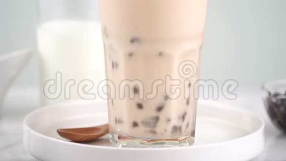 慢动作搅拌木薯珍珠泡奶茶在酒杯美味的台湾流行饮料在明亮的大理石桌上家庭视频的预览图