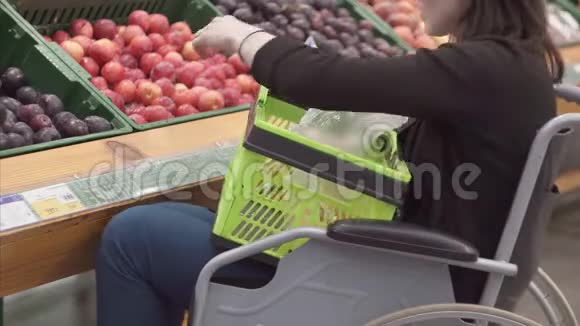 一位残疾妇女在超市的轮椅上购物选择水果并把它们放在一个包裹里关门视频的预览图