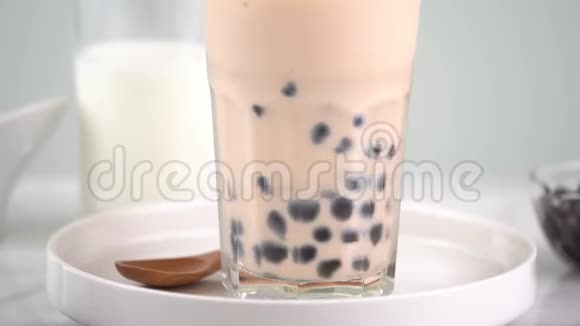 慢动作搅拌木薯珍珠泡奶茶在酒杯中美味的台湾流行饮料在明亮的大理石桌子上家庭视频的预览图