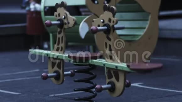 儿童长颈鹿木摇椅孤独地移动没有人在操场上令人毛骨悚然的大气视频的预览图