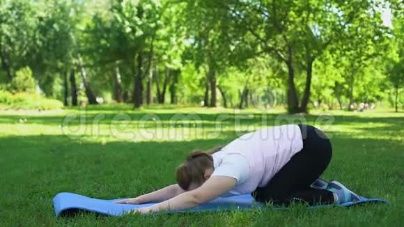 胖女孩笨拙地做伸展运动瑜伽初学者开始健康的生活方式视频的预览图