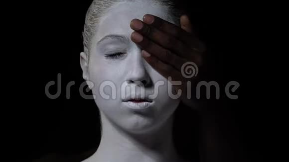 男人用白色的身体艺术从女孩的眼睛移开他的手她环顾四周视频的预览图