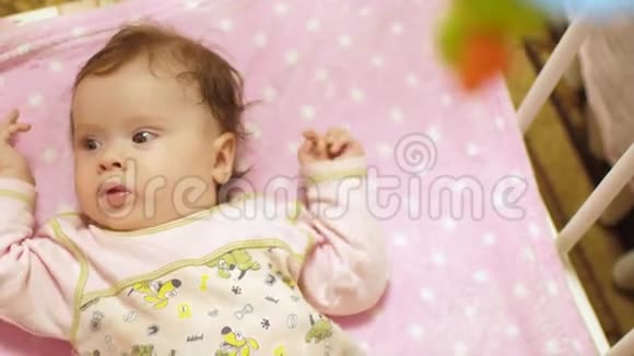 孩子躺在有玩具的婴儿床上侧翻动作缓慢视频的预览图