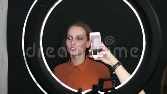 漂亮的模特女士在演播室为智能手机相机摆姿势性感的女人化妆的脸柔软的盒子里的金色短发视频的预览图