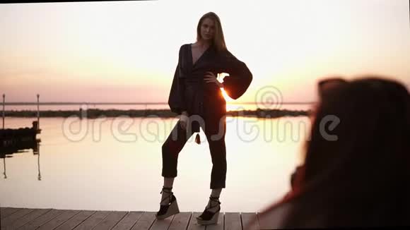 美丽的高大模特穿着黑色连衣裙和凉鞋站在大海前为相机摆好姿势视频的预览图