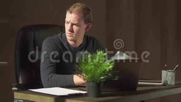 年轻的商人坐在电脑旁的桌子旁的办公室里在处理文件商人坐着视频的预览图