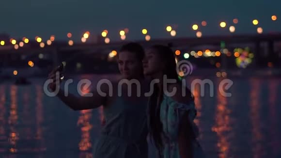 两个女朋友晚上在河边做自拍背景是灯光慢动作视频的预览图