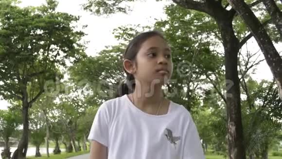 年轻可爱的女孩在公共公园的小路上散步视频的预览图