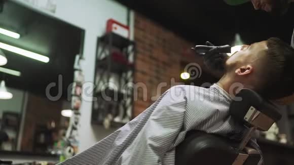 理发师在理发店给顾客刮胡子理发师给顾客理发视频的预览图