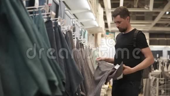 男人在商店里摸毛巾在交易区检查柔软度视频的预览图