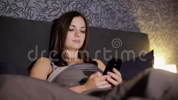 女孩晚上躺在床上上网写短信看照片聊天视频的预览图