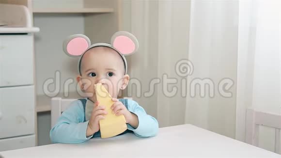 小女孩头上戴着老鼠耳朵啃着有洞洞的黄色奶酪视频的预览图