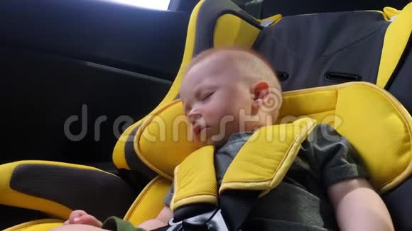 漂亮的小男孩睡在汽车座椅上视频的预览图