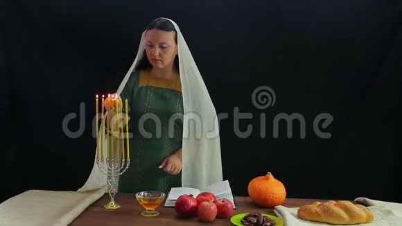 一位犹太妇女在节日的烛台上点燃蜡烛以纪念罗什哈珊并宣读祝福视频的预览图