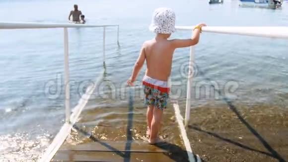 4k视频小男孩走在海上的木制坡道与栏杆视频的预览图
