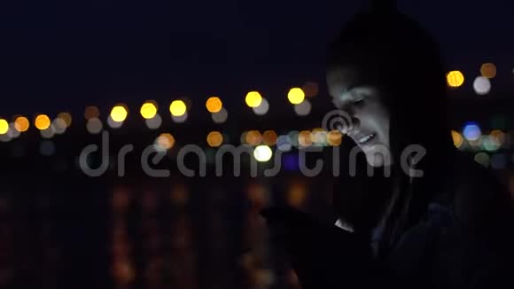 这个女孩在城市的背景下使用一个萨特电话晚上4K视频的预览图