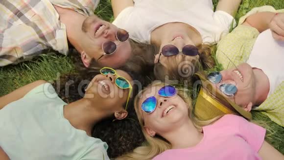 人们躺在草地上享受生活和欢笑太阳眼镜的天空反射视频的预览图