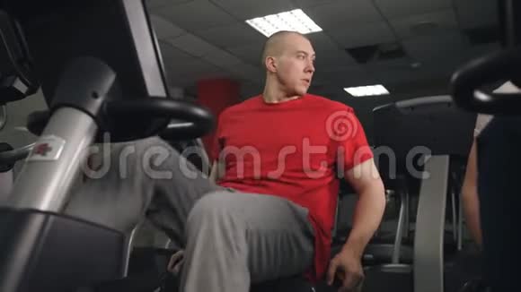 男人在健身房骑自行车锻炼他的腿做有氧训练自行车视频的预览图