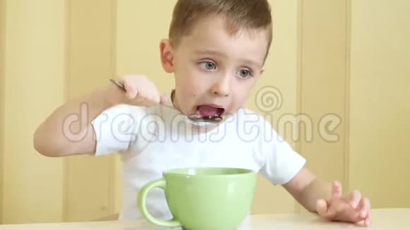 他高兴地用勺子从盘子里吃汤坐在桌子旁伸出拇指特写视频的预览图