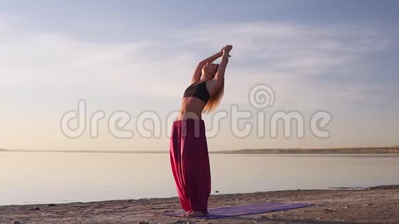 灵活健康的年轻女孩练习瑜伽海滩伸展海洋日出慢动作视频的预览图