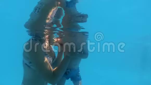 慢动作水下视频小学步男孩学习游泳与母亲支持和抱他视频的预览图