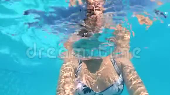 穿比基尼的年轻女子在室外游泳池游泳和手持动作摄像机的慢动作镜头视频的预览图