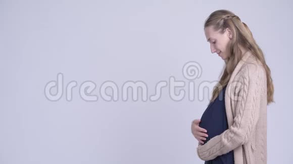 幸福的年轻孕妇看镜头的侧影视频的预览图