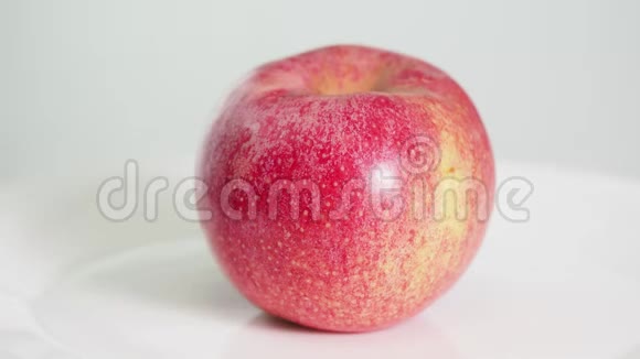 整个熟透的粉红色苹果果实在白色盘子上旋转视频的预览图