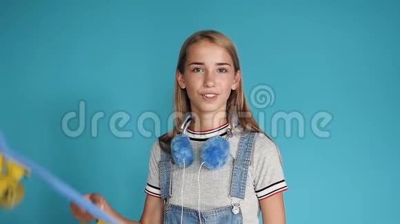 一个少女的肖像她的肩膀上有滑板蓝色背景青少年的空闲时间休闲和体育视频的预览图