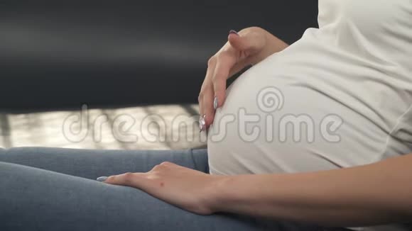 孕妇腹部的近景她的右手慢慢地开始抚摸腹部然后她做了一个视频的预览图