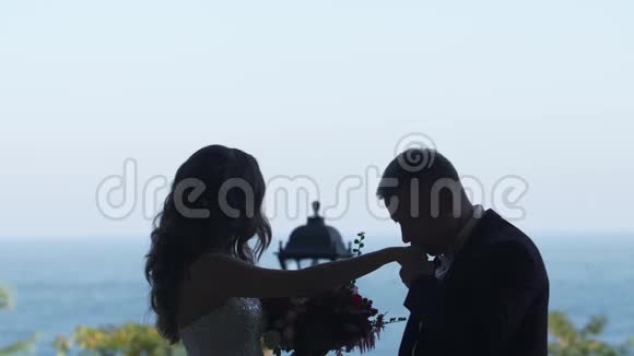 新郎亲吻新娘的手这对夫妇的剪影她在任何地方都看视频的预览图