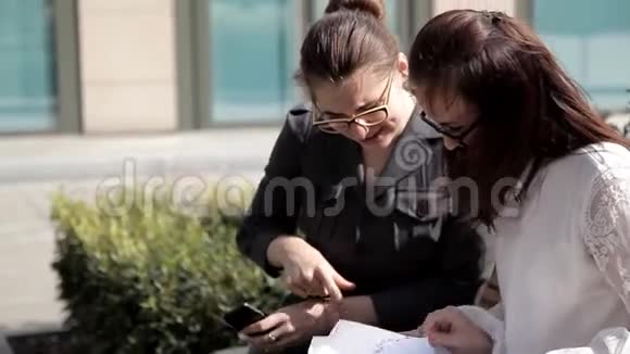两个年轻的商务女孩在商务中心附近的公园进行商务谈判考虑到视频的预览图