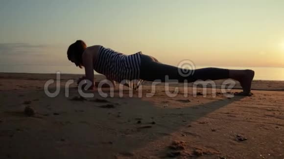 日落时分美丽的运动女子站在沙滩上的木板位置视频的预览图