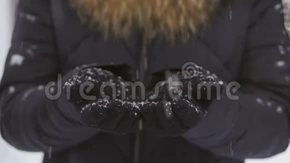 在一场降雪中一个女人把戴着手套的手举在她面前享受着降雪视频的预览图