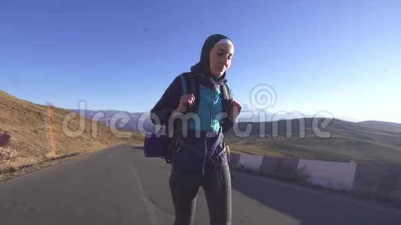 年轻的阿拉伯妇女带着旅游背包在山区的背景下沿着山路旅行视频的预览图