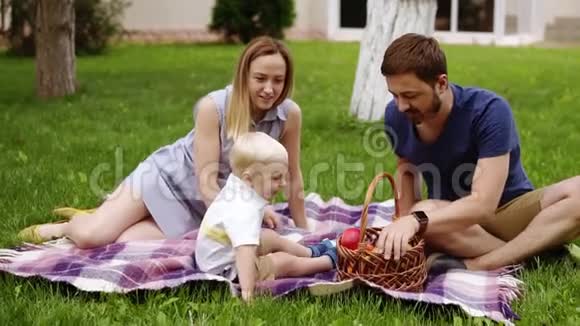 在一个阳光明媚的日子里一家人坐在绿色美丽的草地上野餐他们的儿子坐在附近视频的预览图