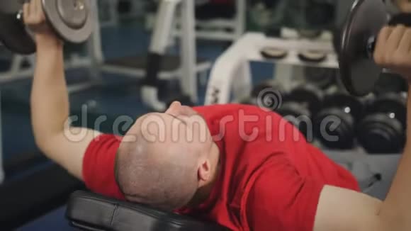 健身馆里的肌肉男把躺在长凳上的重物举起视频的预览图