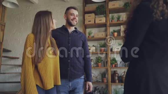 已婚夫妇正在买公寓与女性房地产经纪人握手然后拥抱亲吻和大笑视频的预览图