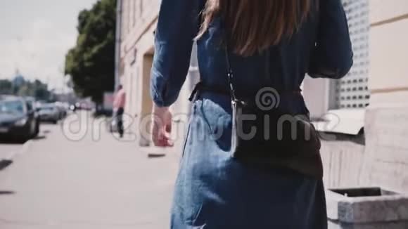 后视年轻女性时尚博主身穿蓝色长裙留着长发时尚包包在街上慢条斯理地走着视频的预览图