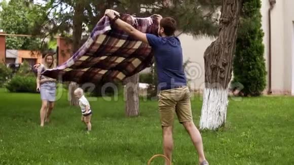 白种人家庭户外父亲母亲和金发的小儿子爸爸铺了一个野餐套野餐篮子草坪视频的预览图
