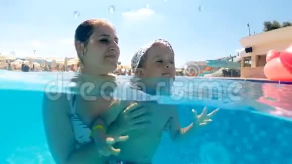阳光明媚的日子里妈妈带着儿子在游泳池游泳欢快的水下动作视频视频的预览图