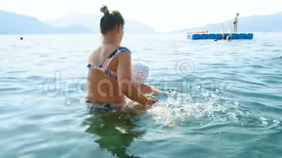 带帽子的小孩学着和妈妈一起在海里游泳视频的预览图