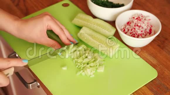 女人正用木桌在厨房里切鲜黄瓜视频的预览图