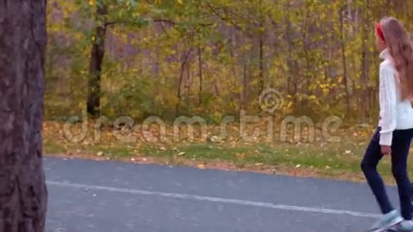 在秋天公园的路上十几岁的女孩骑着陀螺行走视频的预览图