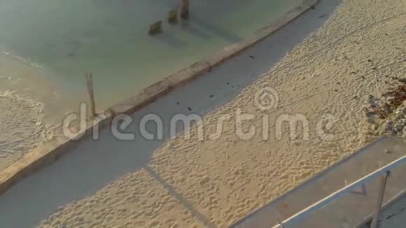 4小岛上一名女子独自步行前往码头在孤零零的白色沙洲上用木制长臂木作支撑视频的预览图