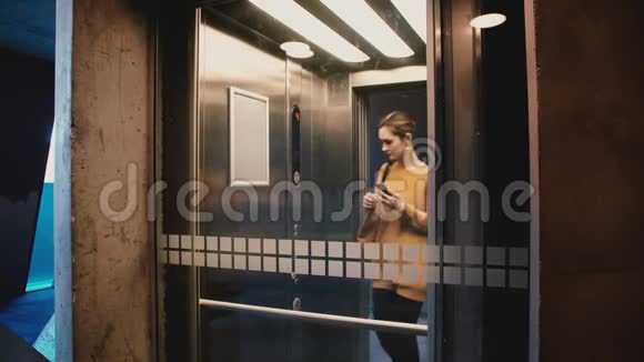 年轻自信的女人进入电梯按下按钮门关闭她骑下来使用智能手机移动办公应用程序视频的预览图